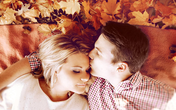 Guy kissing girls forehead in leaves