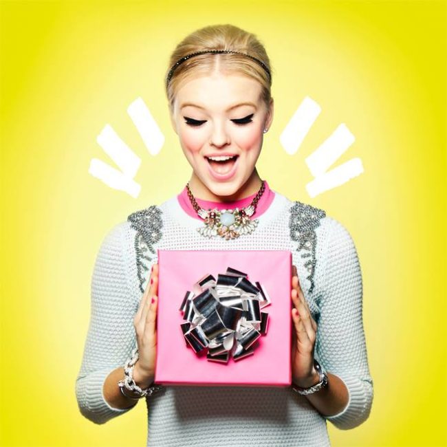 Girl excited to be holding a pink gift box with silver bow